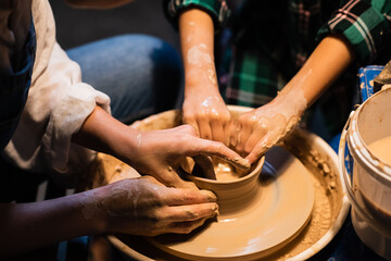 the process of modeling clay dishes on a potter's wheel, the hands of a young girl and a child