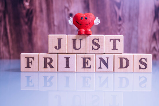 
Text JUST FRIENDS on wood cube blocks. The letters JUST FRIENDS written on the cubes in black letters isolated on a glass surface. JUST FRIENDS text for your desing.