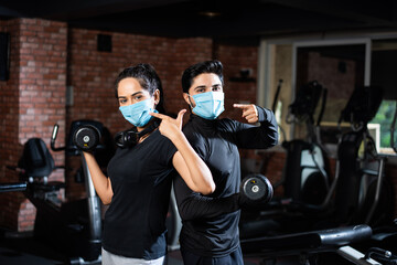 Indian asian young couple wears face mask and working out in the gym