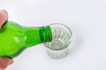 Bottle and glass with soju on white table. Traditional korean alcoholic beverage