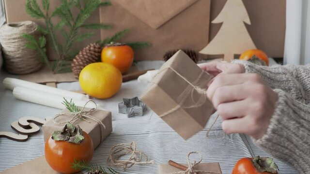 The girl unwraps the gift, unties the bow, close-up. New year's surprise, Christmas atmosphere. Gifts Packed with your own hands. Workshop with Christmas decorations.