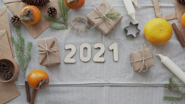 The numbers 2020 change to 2021 on the table among Christmas gifts, top view. Concept 2021 new year is coming. Girl in a sweater lays out 2021, Christmas holiday atmosphere.