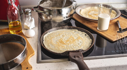 Pancake is cooking in a hot frying pan. Concept of the process of making homemade pancakes in your own kitchen