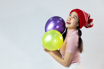 Fototapeta na wymiar Portrait of cute asia woman wearing a red wool hat. Holding a balloon and smiling. On white background
