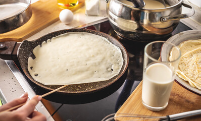 Person is frying pancakes in a hot pan. Concept of the process of making a delicious breakfast at home
