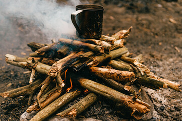Fototapeta premium Tea in metal mug heats up on bonfire