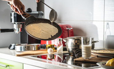 Person pouring the dough into a hot pan and frying homemade pancakes. Concept of making pancakes in your own kitchen