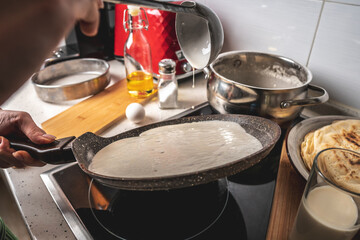 Person is frying pancakes in a hot pan. Concept of the process of making a delicious breakfast at home