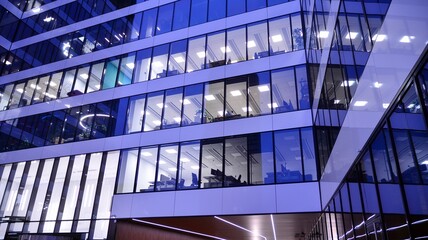 Fototapeta premium Pattern of office buildings windows illuminated at night. Lighting with Glass architecture facade design with reflection in urban city.