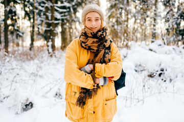 Fototapeta na wymiar Young stylish hipster girl in yellow jacket with a warm scarf posing in the snow forest