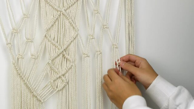 A woman weaves with her own hands a pattern of Macrame threads for decoration or home decor. Home decor idea handmade Macrame cotton.