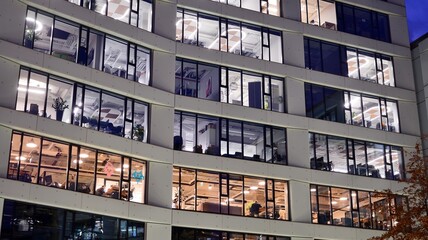 Obraz premium Pattern of office buildings windows illuminated at night. Lighting with Glass architecture facade design with reflection in urban city.