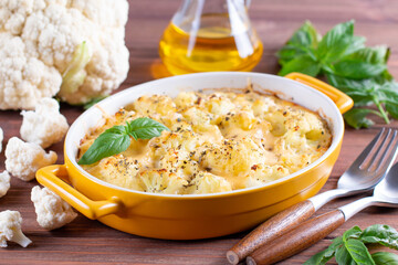 Cauliflower casserole with cheese and milk sauce in a baking dish on table