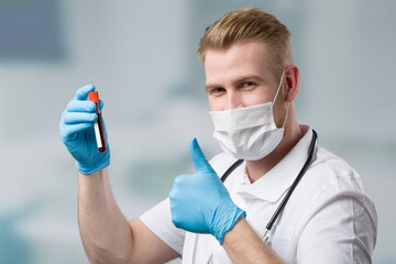 doctor or scientist with medical face mask, medical gloves and stethoscope presents a blood probe...