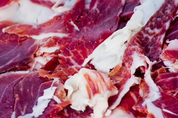 Portions of ham on wooden tray on white background