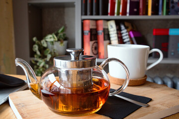 Cozy remote working morning in cafe - cup of hot herbal tea, laptop on desk and books