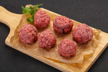 Raw meatball over wooden background