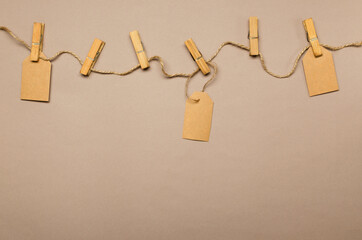 Rope, pins and paper labels on the light brown background.Empty space