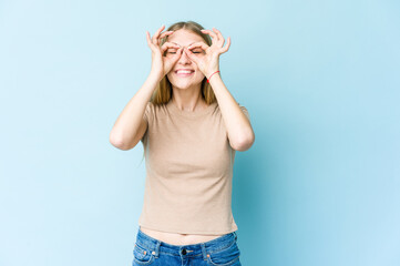 Young blonde woman isolated on blue background excited keeping ok gesture on eye.