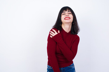 People, lifestyle, youth and happiness concept. Shy pretty Young beautiful Caucasian woman wearing red T-shirt against white wall, feeling happy hugging herself.