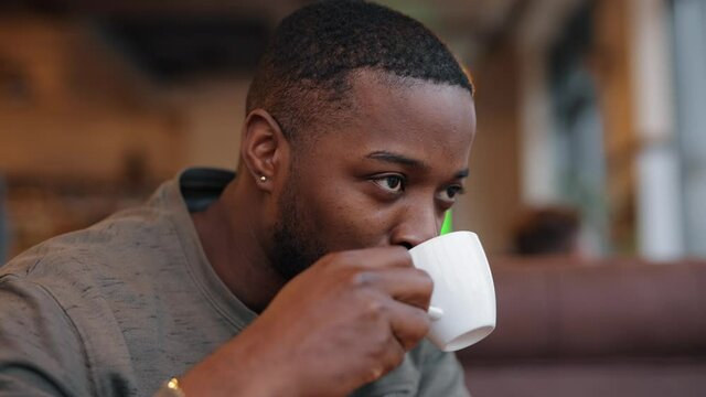 African American man drinking tea with pleasure sitting in a cafe in slow motion