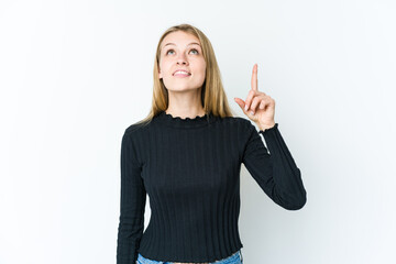 Young blonde woman isolated on white background indicates with both fore fingers up showing a blank...
