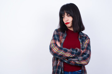 Displeased Young Caucasian beautiful woman wearing plaid shirt against white background with bad attitude, arms crossed looking sideways. Negative human emotion facial expression feelings.