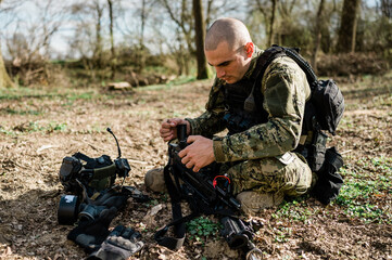 Soldier un Cropat uniform fixing his assault rifle G36 in the forest on a sunny day.