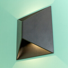 One glowing black modern metal led lamp on the turquoise color wall. Free space.