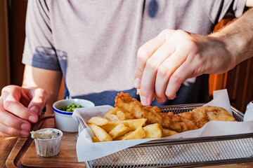 Man's hand sprinkling with lemon fish and chips