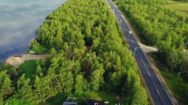 Road trip on empty highway aligned by green pine trees along Tornio river