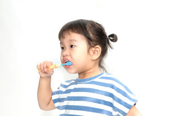 A cute little Asian girl brushing her teeth isolated on white background. Healthy teeth concept.