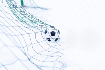 The classic soccer ball scores a goal. Football in the winter outdoors in snowy weather. Outdoor football, a hobby for children and adults © MMM