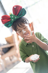 An Asian boy eats and plays cream.