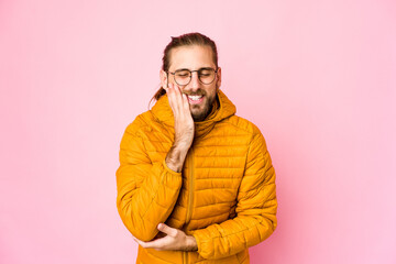 Young man with long hair look laughs happily and has fun keeping hands on stomach.