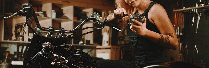 Woman mechanic repairing a motorcycle in workshop