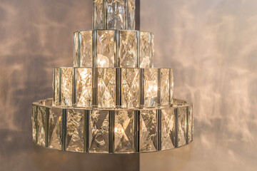 Close-up of the glowing luxury expensive chandelier from a crystal ceiling lampshade. Classic style in a modern interior. Indoors. Warm soft light.