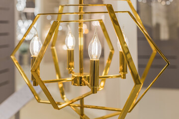 Luminous ceiling cover made of yellow gold metal with transparent glass lamps in the form of candles. Concept of interior decoration. Inside. Close up.
