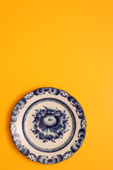 Top view of a blue plate on a yellow background. Gzhel