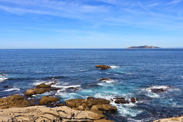 view of the ocean from the rocky shore with an island in the background. Galicia, Spain