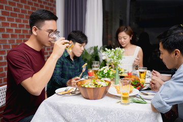 Asian group of friends to have a party and have dinner in the room.  He is drinking beer.