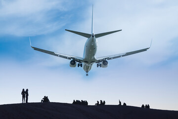 Airrcraft low in flight, humans on the ground