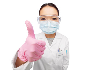 medicine, profession and healthcare concept - asian female doctor or scientist wearing face protective medical mask, gloves and goggles showing thumbs up over white background