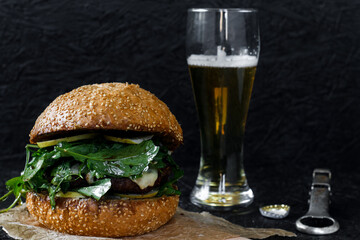 Burger and beer in a glass on a dark background. Hamburger
