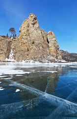 Fototapeta na wymiar A beautiful winter landscape of frozen Lake Baikal with transparent ice near the famous Bell Tower Rock is a natural landmark of Peschanaya Bay or Sandy Bay. Natural background. Ice journey