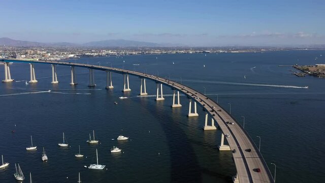 Drone Flying Above Vehicles Driving At Coronado Bridge Over San Diego Bay With Chula Vista And National City In Background In San Diego California, USA. - aerial