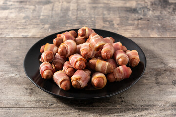Pig in blankets. Sausages wrapped in smoked bacon on wooden table