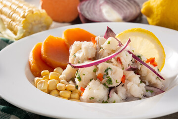 Traditional peruvian ceviche with fish, sweet potato, corn and vegetables on wooden table
