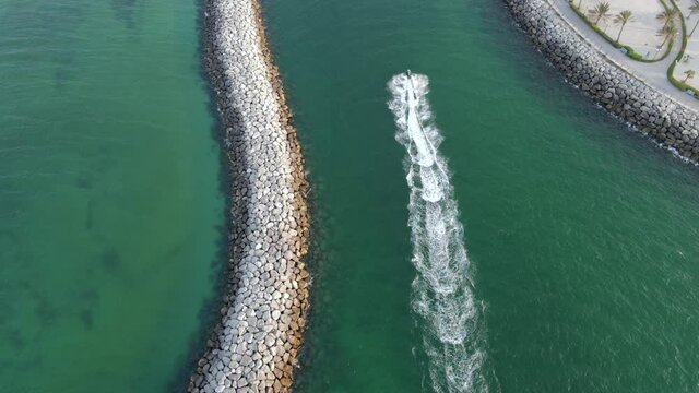 Drone Camera follows the jet-ski, watersport at paradise, coast blue-green crystal clear water of Dubai's Mamzar beach, Arabian Sea, top tourist attraction, 4k Footage 