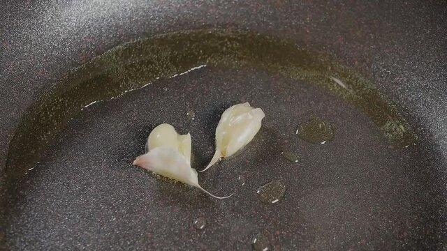 Two cloves of garlic are fried in olive oil in a hot pan